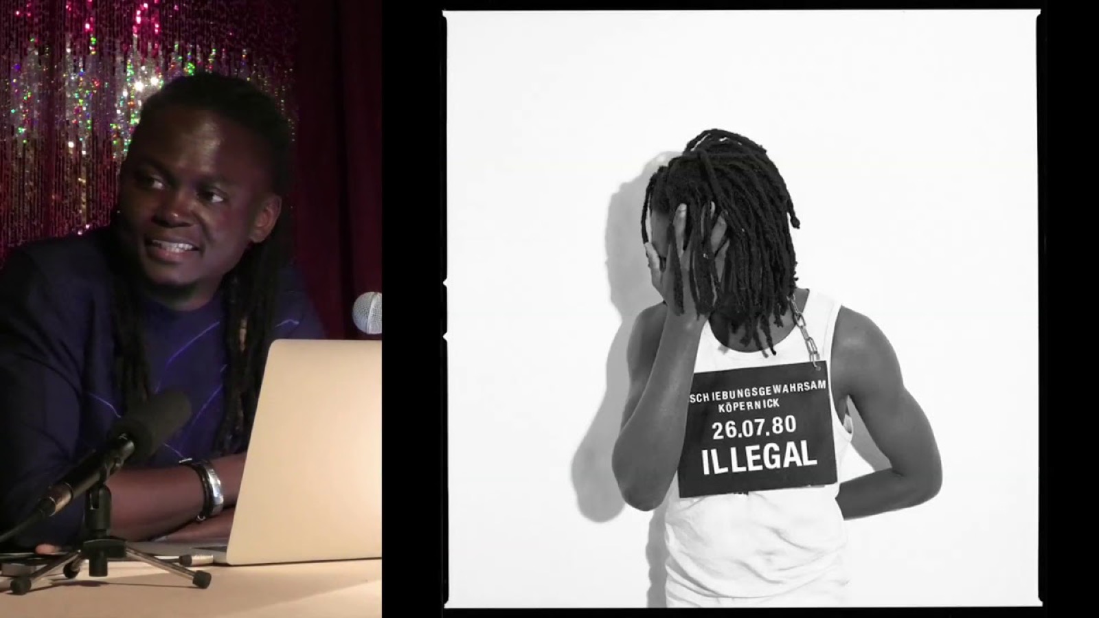 Emeka Okereke speaks at a laptop beside a large projected photograph of a figure seen from behind, wearing a vest printed with the word ILLEGAL and a date.