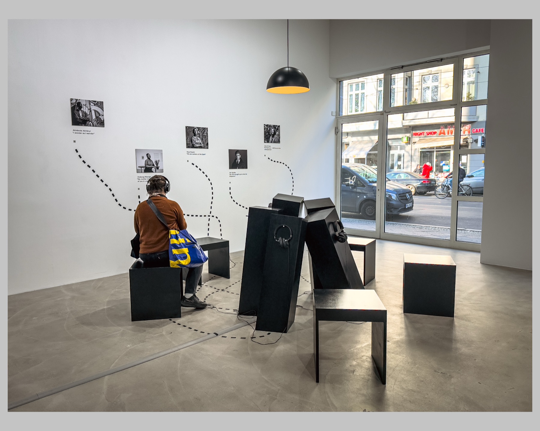 The installation seen from inside the room towards the windows of Chausseestraße, with a visitor seated and listening.