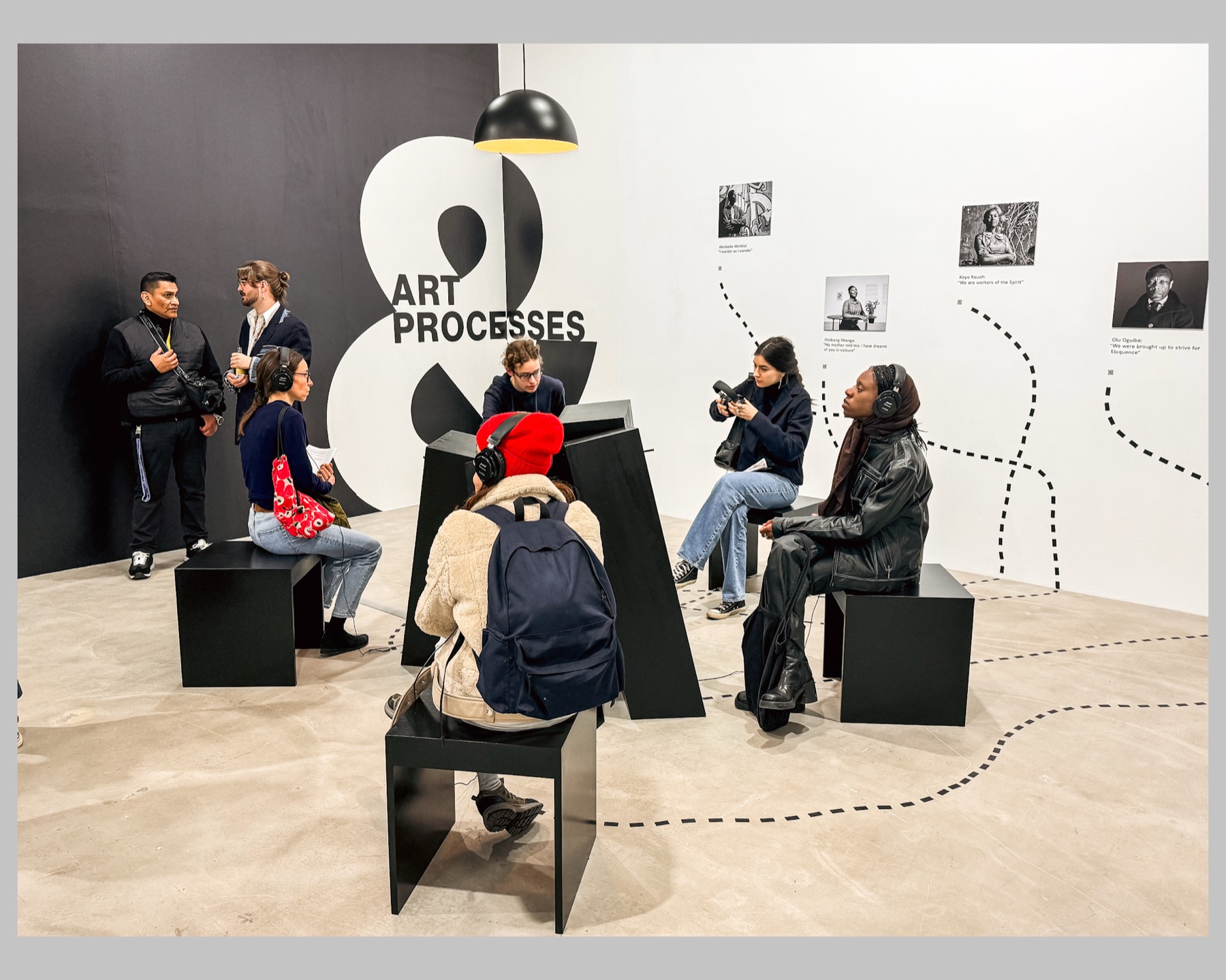 Visitors seated at the listening positions during the opening, headphones on, under the suspended lamp.